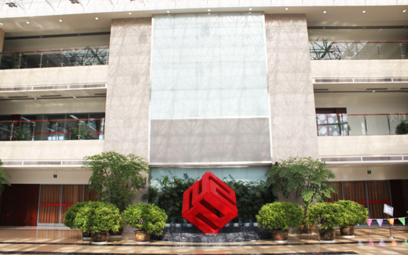Lobi kantor pusat FMWorld bersih dan terang, dengan logo kubik merah yang menonjol di tengahnya.