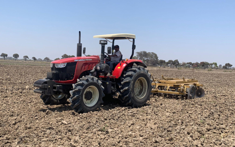 Traktor FMWorld WD1304 dengan garu cakram memecah gumpalan tanah untuk persiapan persemaian.