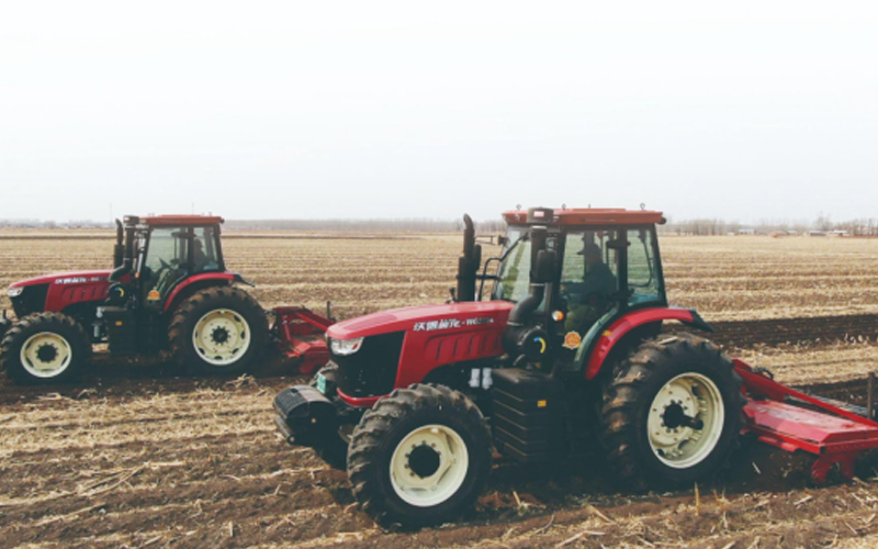 Dua traktor FM World sedang membajak ladang.