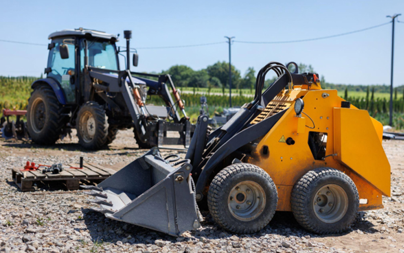 Traktor kecil dengan ember untuk memindahkan tanah, rumput, dan material curah