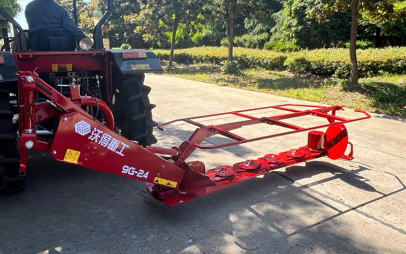 Traktor merah dengan mesin pemotong rumput terpasang World 9G-24 diparkir di permukaan beraspal.
